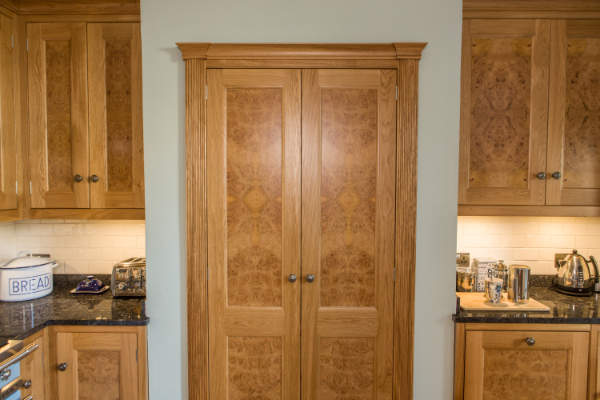 Larder cupoard with doors closed, the doors have burr oak veneers in the panels