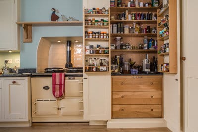 Large larder cupboard with doors open revealing 3 storage drawers shelving for ingredients and cooking equipment, on the reverse of the doors there are 2 large spice racks.