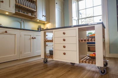 Side view of mobile kitchen island with granite worktop, shelving, and four storage drawers