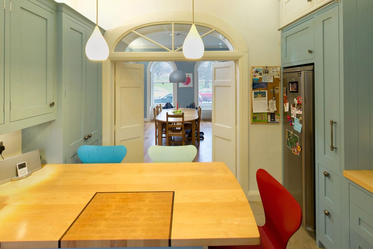 Kitchen with burr elm veneers on door panels, showing a curved run of cabinets with marble worktops and integrated oven and hob